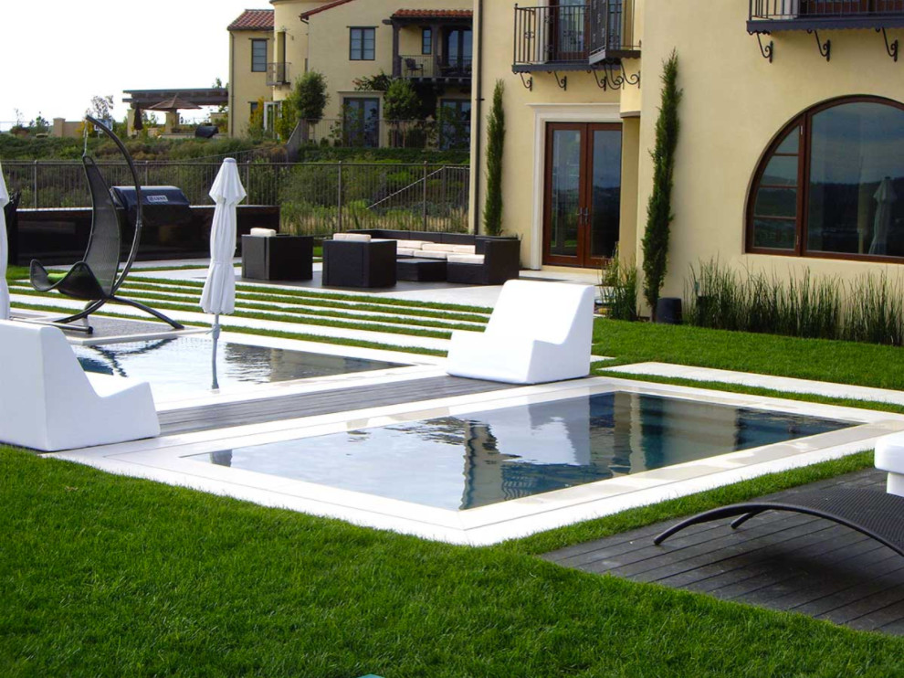 Ispirazione per una piscina naturale contemporanea rettangolare di medie dimensioni e dietro casa con una vasca idromassaggio e lastre di cemento