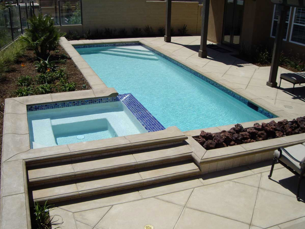 Foto di una piscina naturale mediterranea rettangolare di medie dimensioni e dietro casa con una vasca idromassaggio e lastre di cemento