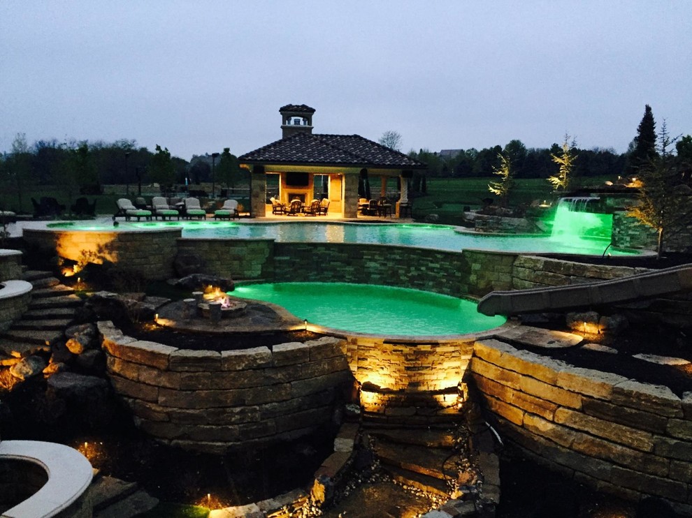 Medium sized classic back custom shaped above ground swimming pool in Kansas City with a water feature and natural stone paving.