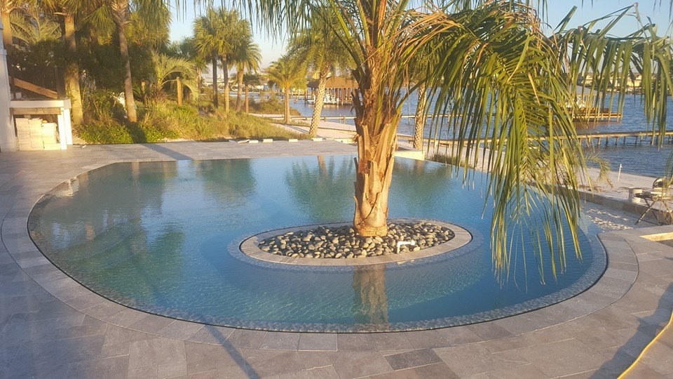 Стильный дизайн: естественный, круглый бассейн среднего размера на заднем дворе в морском стиле с фонтаном и покрытием из каменной брусчатки - последний тренд