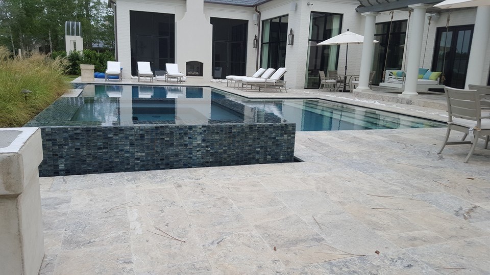 Пример оригинального дизайна: большой прямоугольный бассейн-инфинити на заднем дворе в современном стиле с фонтаном и покрытием из каменной брусчатки