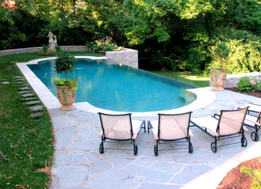 Immagine di una piscina a sfioro infinito chic personalizzata di medie dimensioni e dietro casa con pavimentazioni in pietra naturale