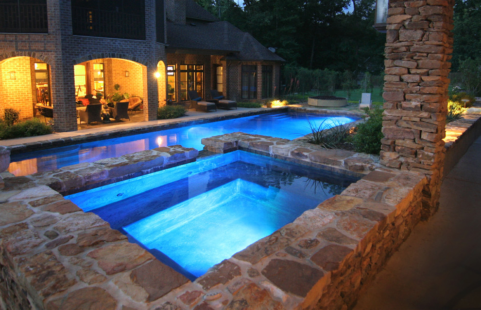 Large tuscan backyard stone and rectangular lap hot tub photo in Houston