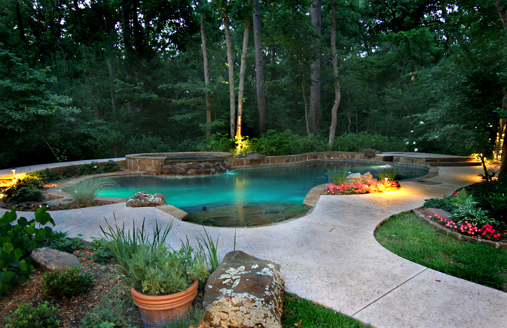Ispirazione per una grande piscina naturale tropicale a "C" dietro casa con una vasca idromassaggio e cemento stampato