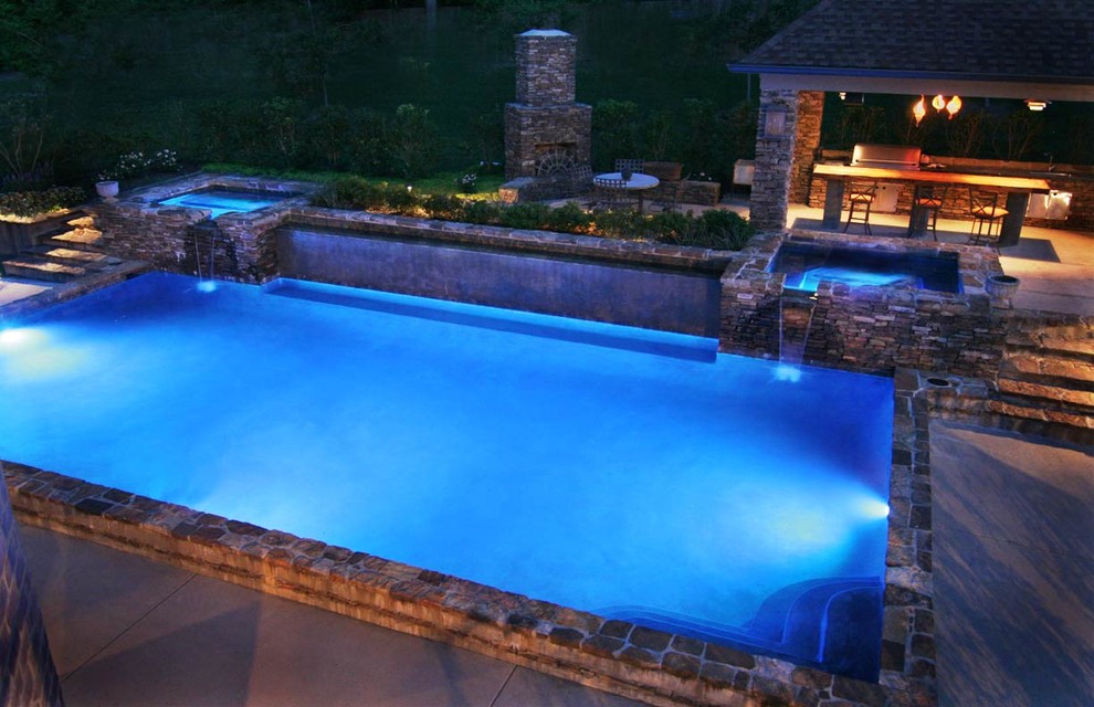 Photo of a large mediterranean back rectangular lengths hot tub in Houston with natural stone paving.