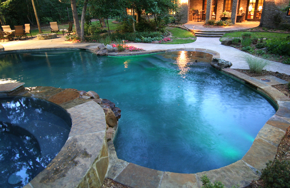 Cette photo montre une grande piscine naturelle et arrière exotique en forme de haricot avec un bain bouillonnant et du béton estampé.