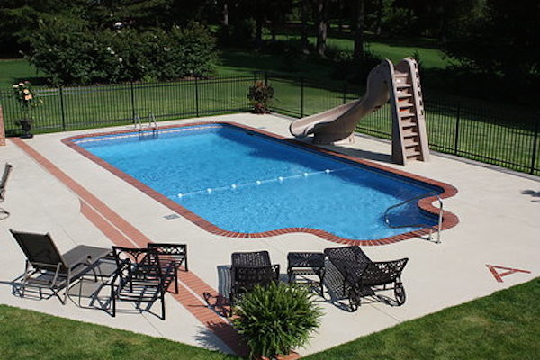 Imagen de piscina con tobogán de tamaño medio a medida con suelo de hormigón estampado