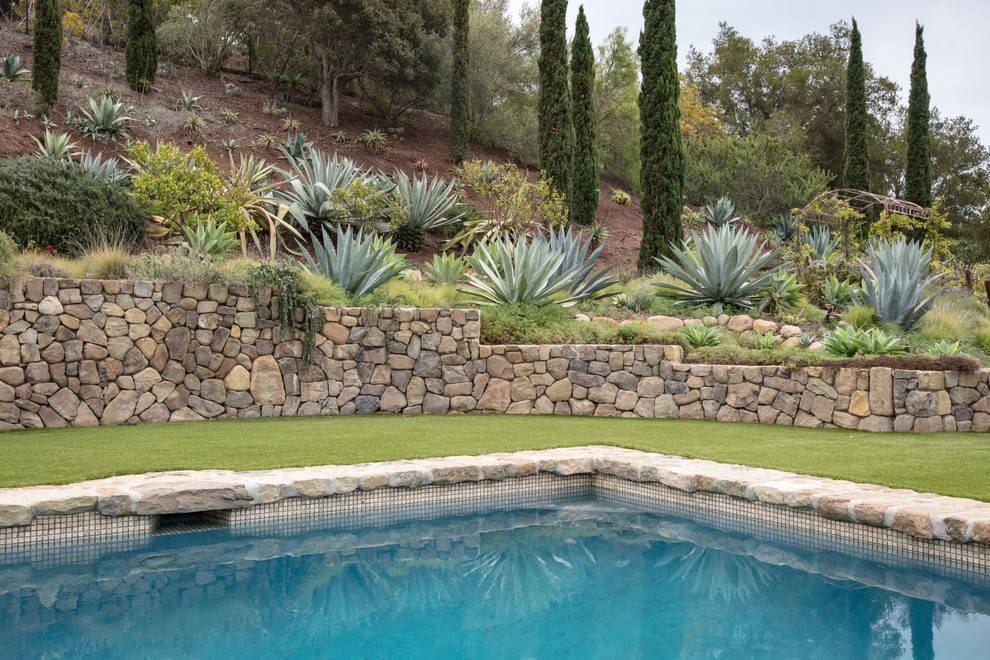 Imagen de piscina mediterránea grande rectangular con adoquines de piedra natural