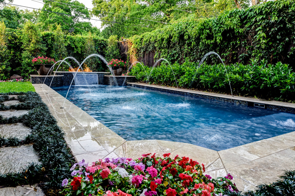 Mid-sized island style backyard stone and rectangular lap pool fountain photo in Dallas
