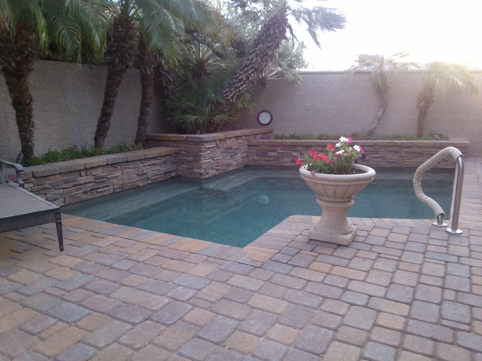 Klassischer Pool hinter dem Haus in L-Form mit Natursteinplatten in Sonstige