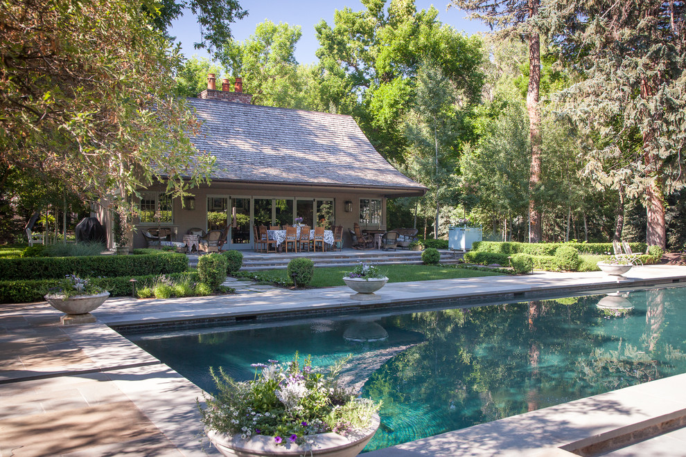Foto de piscina clásica extra grande rectangular en patio trasero con paisajismo de piscina y losas de hormigón