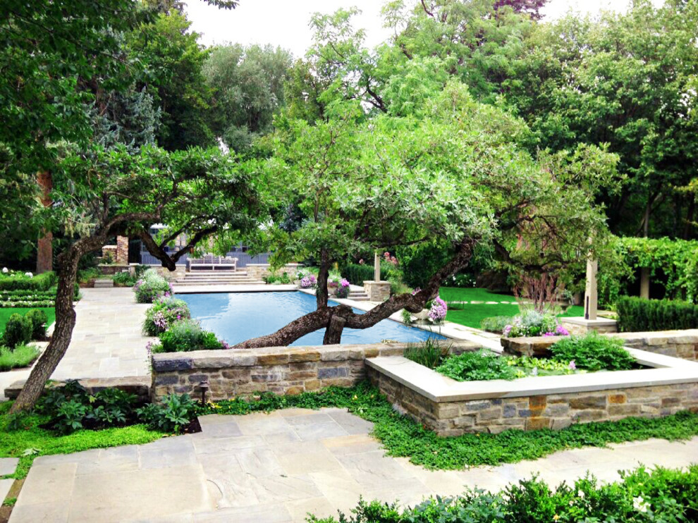 Ejemplo de piscina clásica extra grande rectangular en patio trasero con paisajismo de piscina y adoquines de piedra natural
