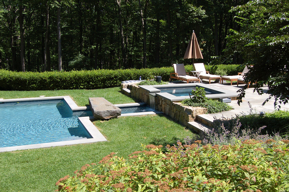 Cette image montre une piscine hors-sol et arrière traditionnelle de taille moyenne et rectangle avec un bain bouillonnant et des pavés en pierre naturelle.