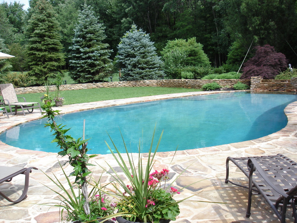 Klassisk inredning av en anpassad pool på baksidan av huset, med naturstensplattor