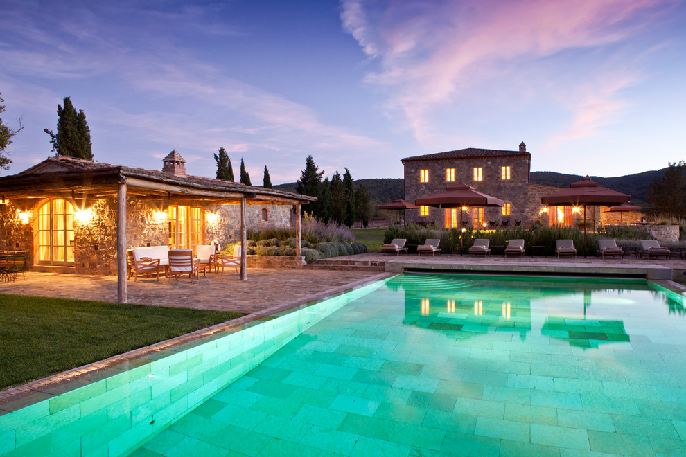 Immagine di un'ampia piscina naturale mediterranea rettangolare dietro casa con fontane e pavimentazioni in pietra naturale