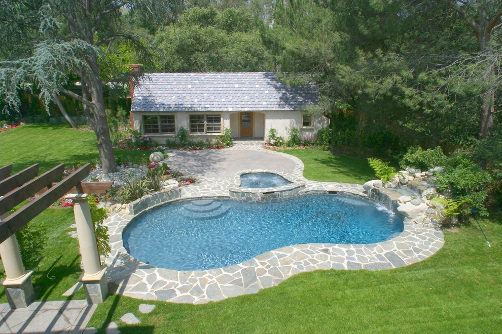 Elegant stone and custom-shaped pool photo in Orange County