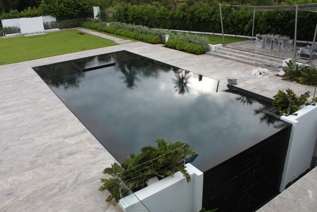 Cette photo montre une grande piscine à débordement et arrière moderne rectangle avec du carrelage.