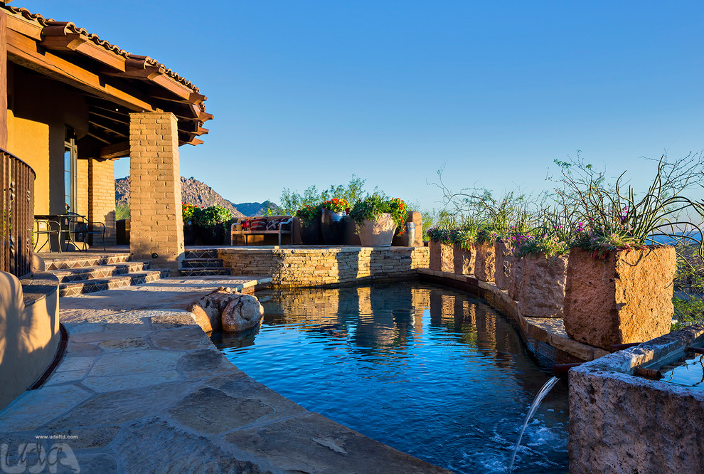Ejemplo de piscina con fuente natural de estilo americano a medida en patio trasero con adoquines de piedra natural