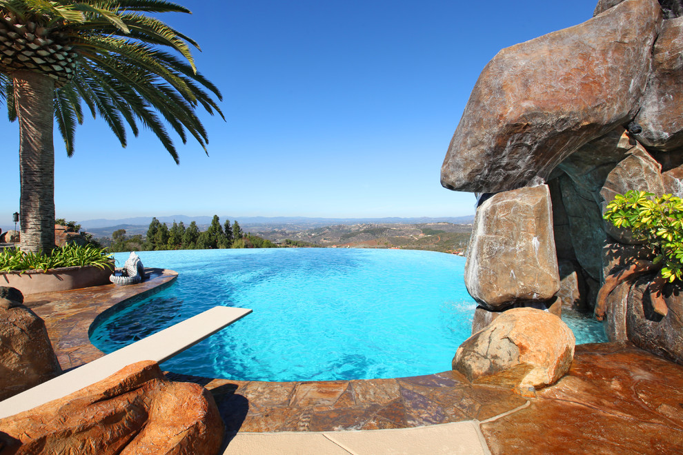 Ejemplo de piscina infinita tropical a medida con adoquines de piedra natural