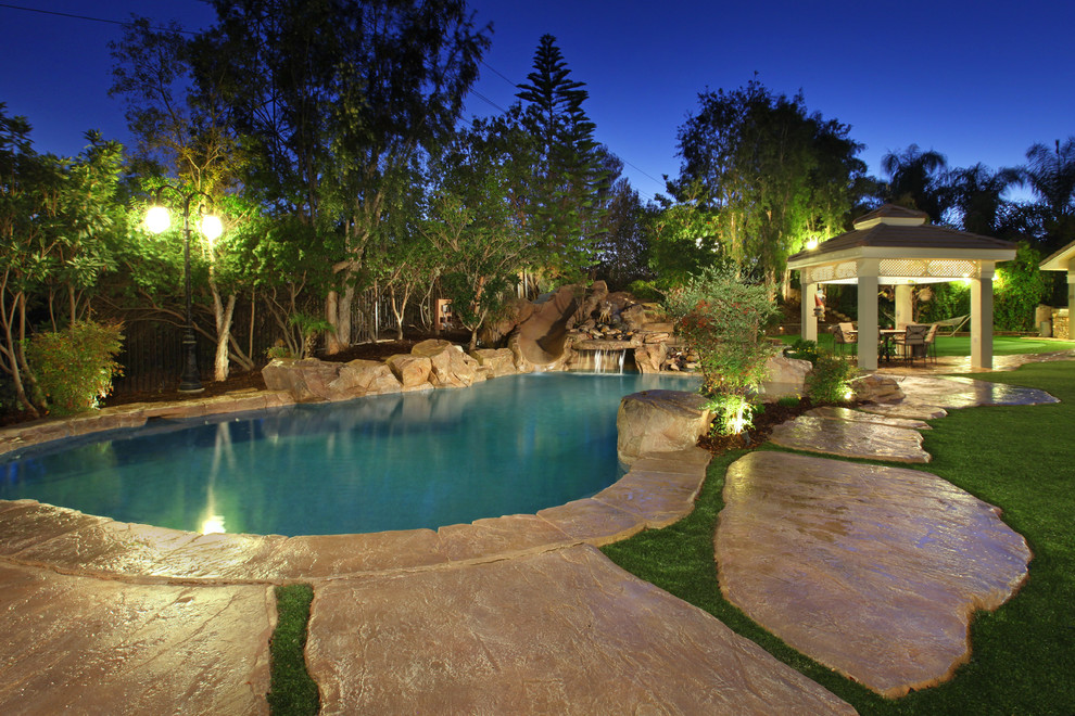 Rustic custom shaped natural swimming pool in Orange County with a water slide.