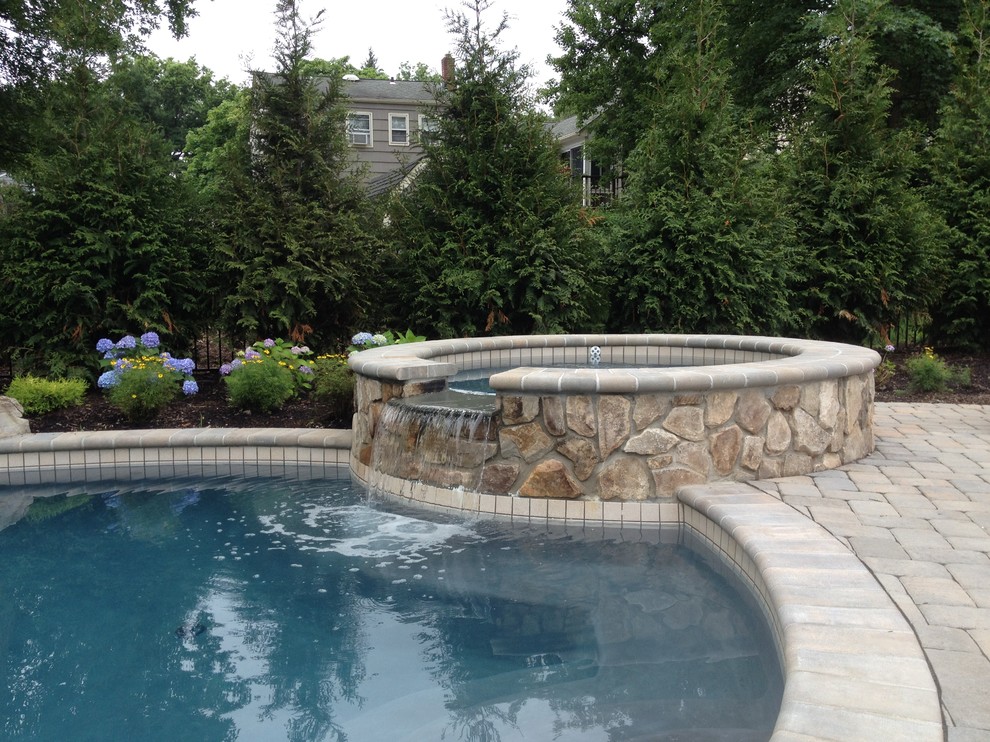 Inspiration for a large classic back round natural hot tub in New York with natural stone paving.