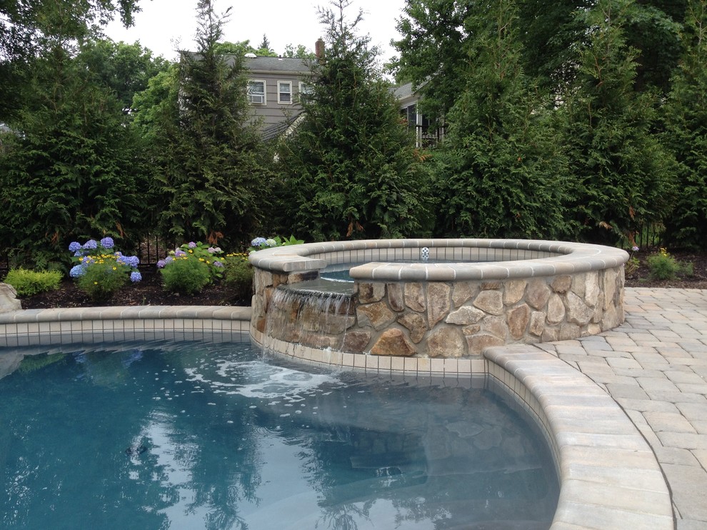 Ejemplo de piscinas y jacuzzis naturales tradicionales renovados grandes redondeados en patio trasero con adoquines de piedra natural