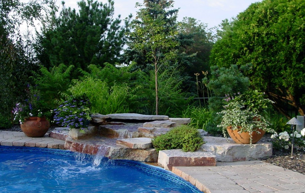 Пример оригинального дизайна: большой естественный бассейн в форме фасоли на заднем дворе в классическом стиле с фонтаном и покрытием из каменной брусчатки