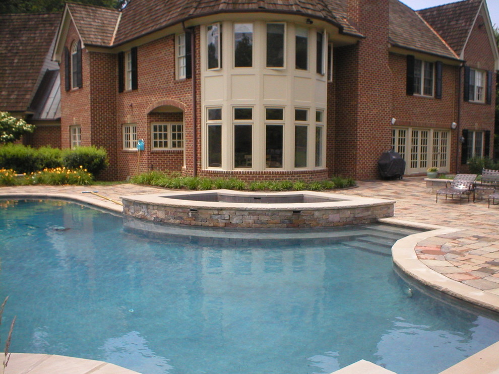 Idées déco pour une piscine latérale classique de taille moyenne et sur mesure avec un bain bouillonnant et des pavés en pierre naturelle.