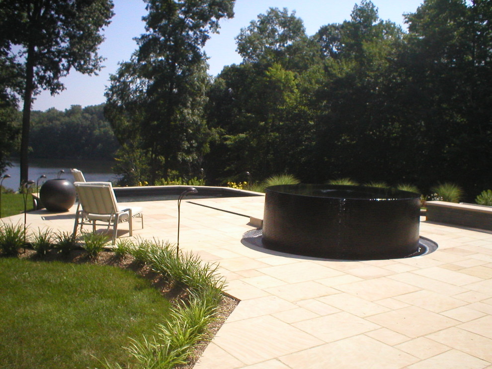 Modelo de piscinas y jacuzzis infinitos actuales en patio trasero con adoquines de piedra natural