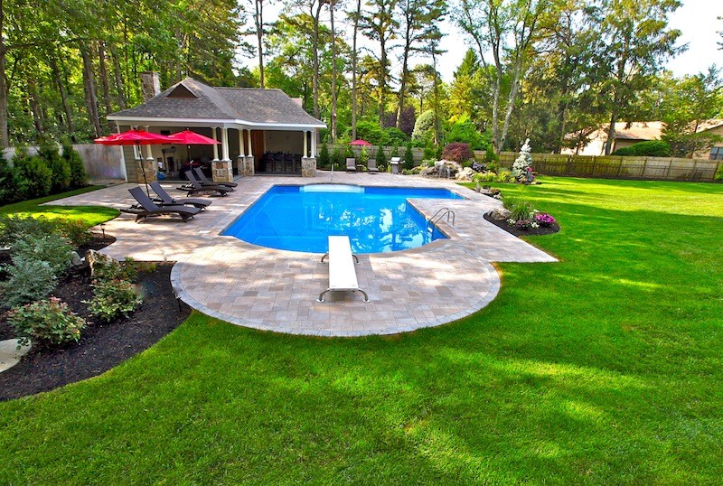 Источник вдохновения для домашнего уюта: большой угловой бассейн на заднем дворе в стиле модернизм с домиком у бассейна и покрытием из каменной брусчатки