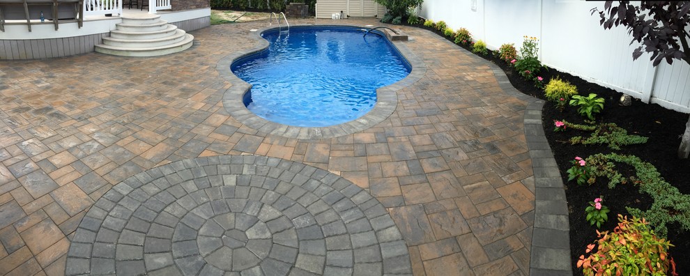 Large contemporary back custom shaped natural swimming pool in New York with a water feature and concrete paving.