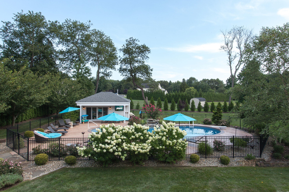 Diseño de casa de la piscina y piscina clásica renovada de tamaño medio tipo riñón en patio trasero con adoquines de hormigón