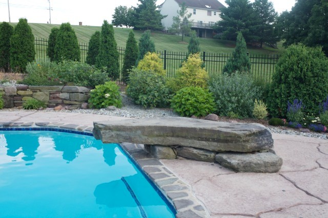 Imagen de piscina clásica a medida en patio trasero con adoquines de hormigón
