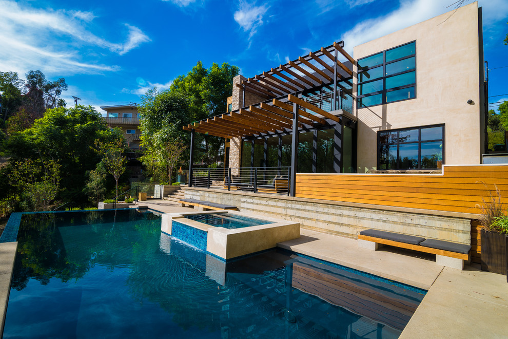 Diseño de piscina con fuente infinita contemporánea de tamaño medio rectangular en patio trasero con losas de hormigón