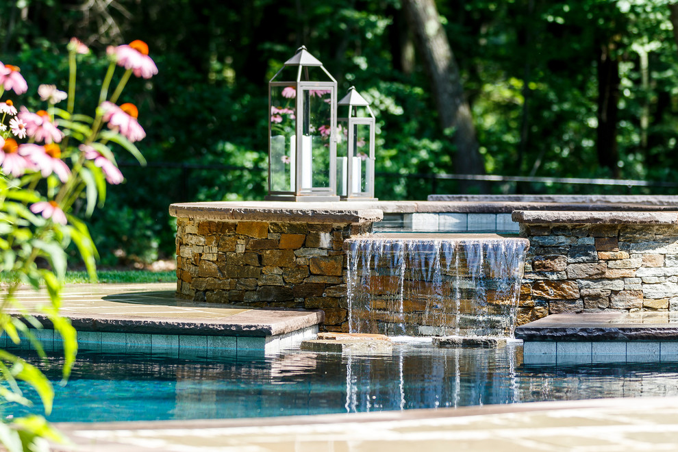 Foto di una piscina a sfioro infinito classica a "C" dietro casa e di medie dimensioni con fontane e pavimentazioni in cemento