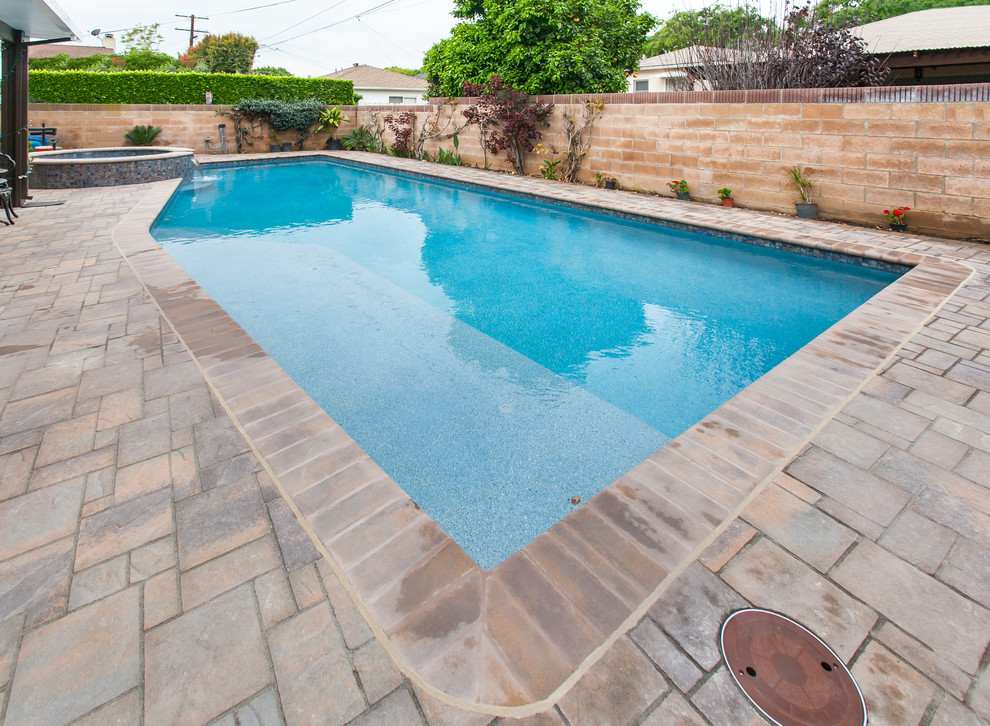 Esempio di una piscina monocorsia chic rettangolare di medie dimensioni e dietro casa con una vasca idromassaggio e pavimentazioni in cemento