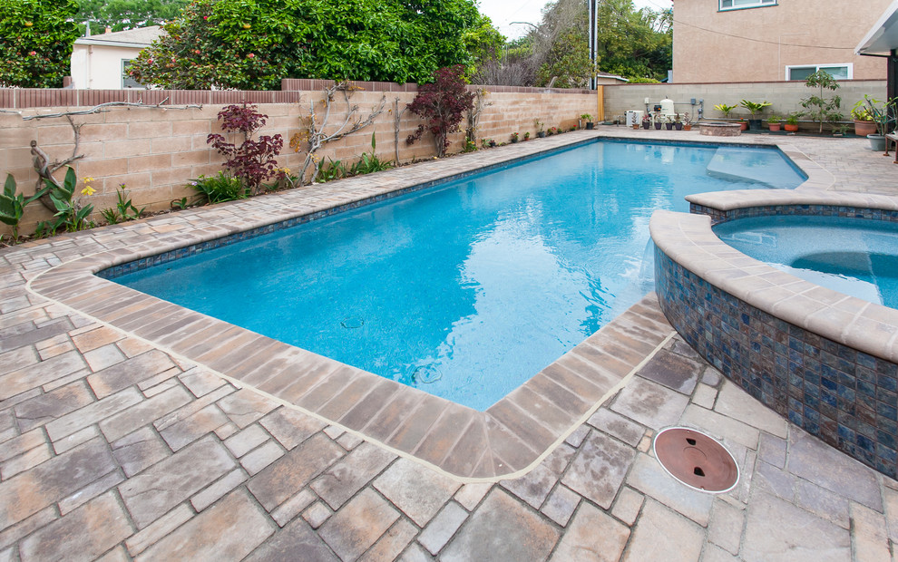Esempio di una piscina monocorsia chic rettangolare di medie dimensioni e dietro casa con una vasca idromassaggio e pavimentazioni in cemento