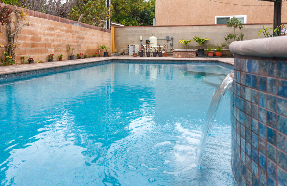 Ispirazione per una piscina monocorsia chic rettangolare di medie dimensioni e dietro casa con una vasca idromassaggio e pavimentazioni in cemento