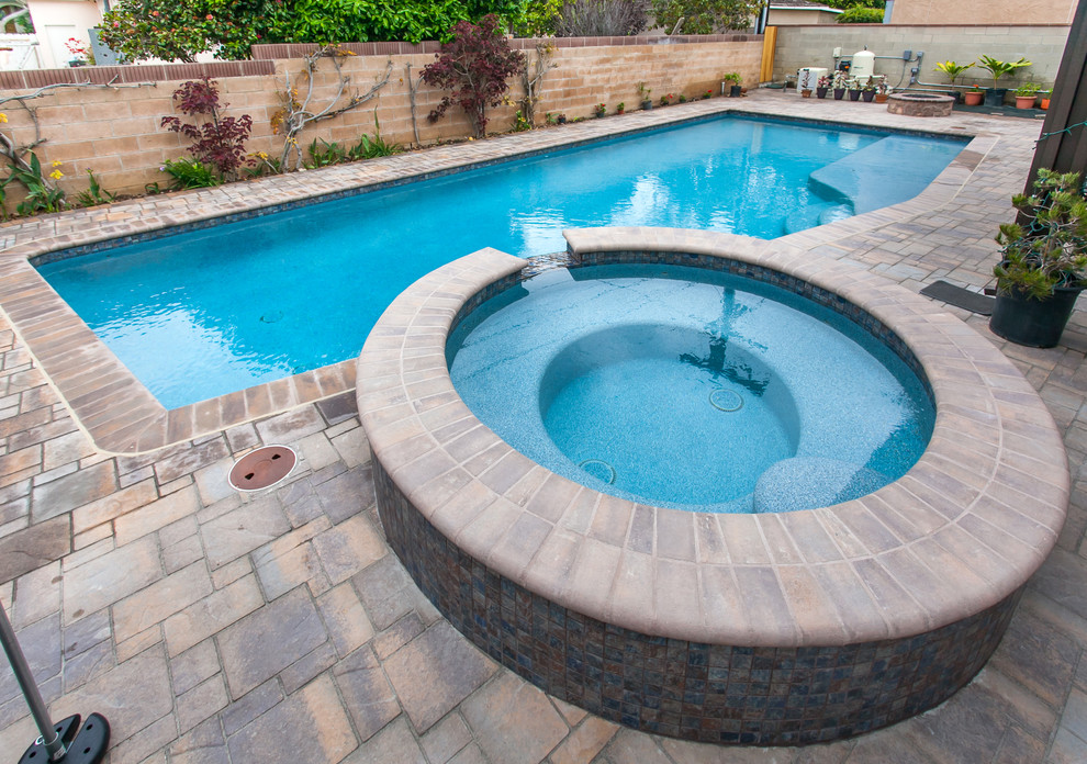 Ispirazione per una piscina monocorsia tradizionale rettangolare di medie dimensioni e dietro casa con una vasca idromassaggio e pavimentazioni in cemento
