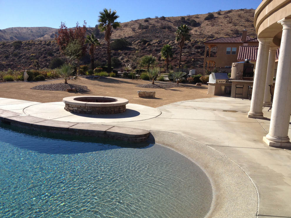 Modelo de piscina clásica renovada grande a medida en patio trasero con losas de hormigón