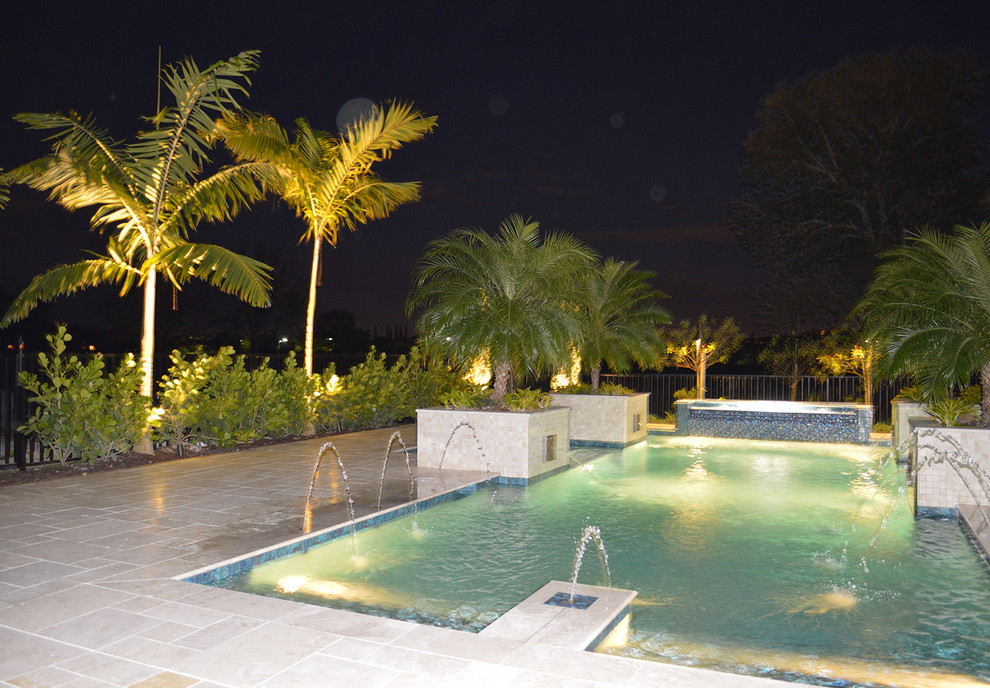 Imagen de piscina con fuente alargada exótica grande rectangular en patio trasero con suelo de baldosas