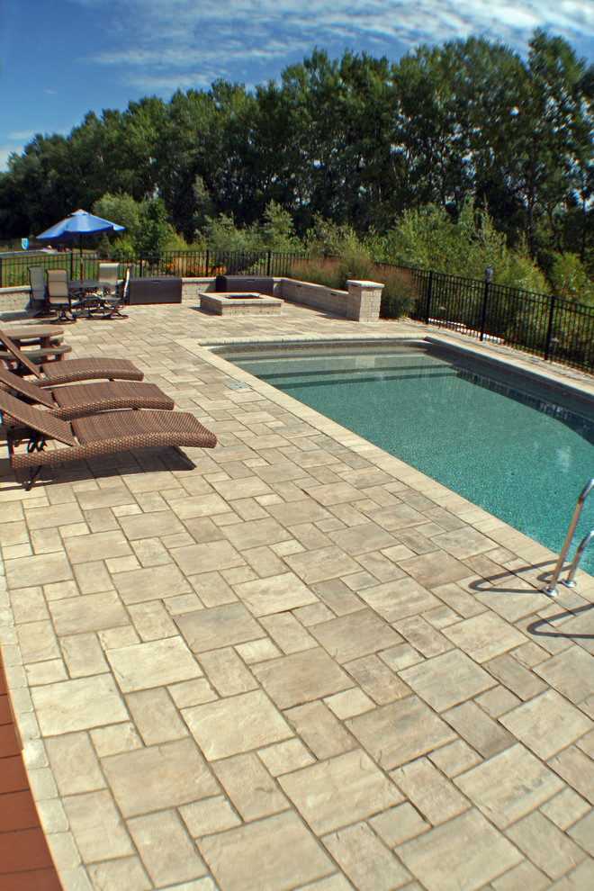Ejemplo de piscina alargada clásica de tamaño medio rectangular en patio trasero con suelo de baldosas