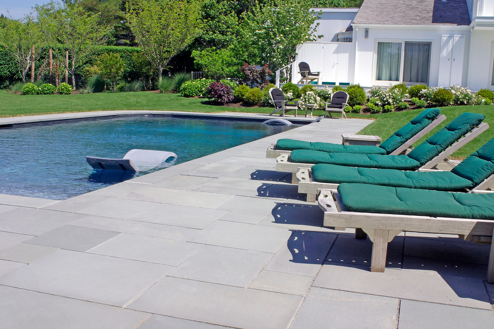 Diseño de piscina elevada clásica grande rectangular en patio trasero con adoquines de piedra natural