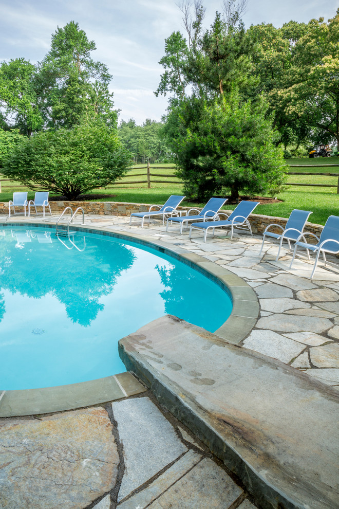 Diseño de piscina con fuente alargada contemporánea redondeada en patio trasero con adoquines de piedra natural