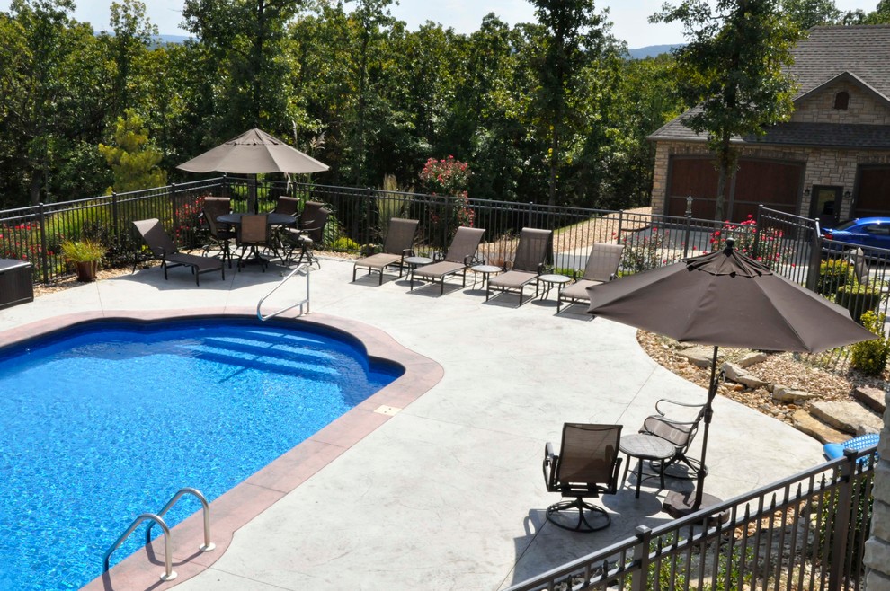 Foto de piscina alargada tradicional renovada grande a medida en patio trasero con suelo de hormigón estampado
