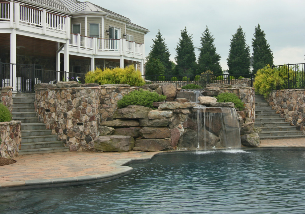 Foto på en stor funkis pool på baksidan av huset, med en fontän och marksten i betong