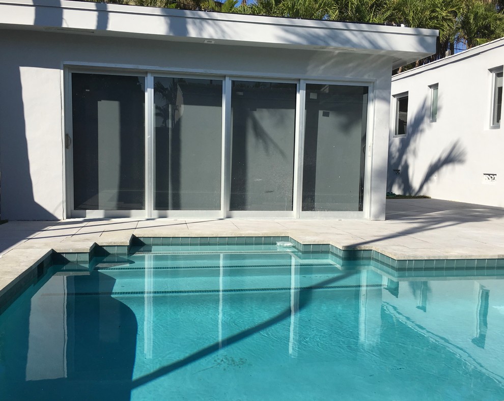 Modelo de piscina alargada moderna grande rectangular en patio trasero con suelo de baldosas
