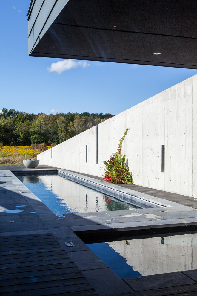 Foto di una grande piscina monocorsia minimalista rettangolare nel cortile laterale con una vasca idromassaggio e pavimentazioni in pietra naturale