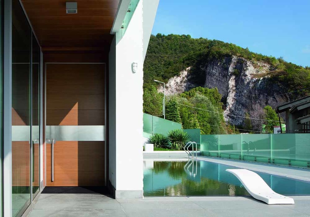 Imagen de piscina minimalista de tamaño medio rectangular en patio lateral con adoquines de hormigón