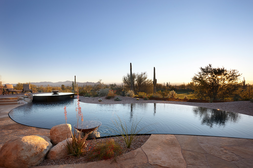 Foto de piscina con fuente infinita de estilo americano grande a medida en patio trasero con adoquines de hormigón
